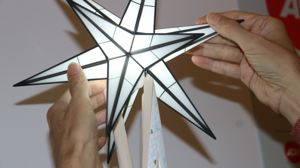 Detall d'unes mans tocant l'estrella que corona la maqueta tàctil de la Torre de Maria de la Sagrada Família | Eli Don, ACN